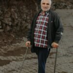 Elderly Man Standing with Crutches on the Sidewalk